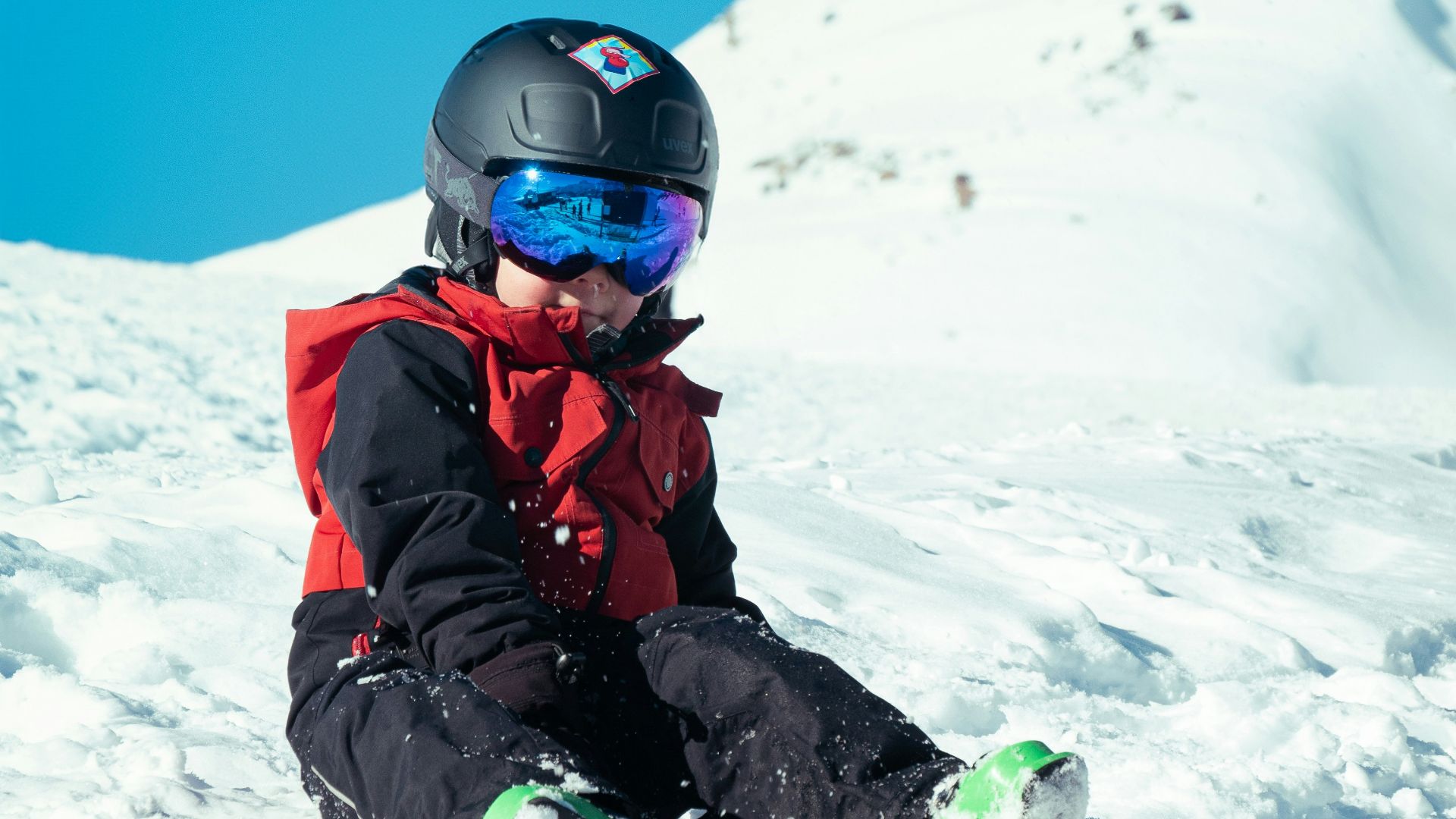 a young child sitting in the snow on a snowboard
