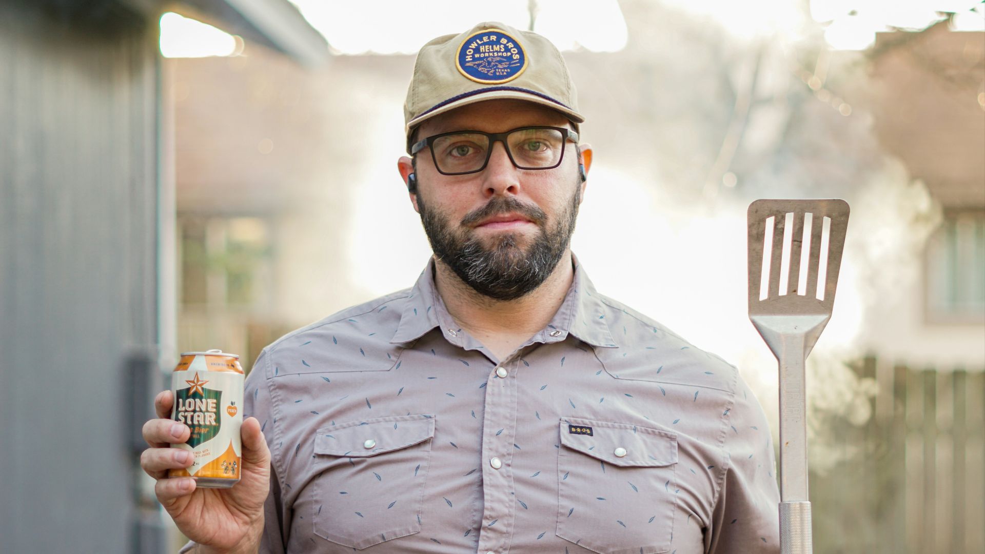 man in gray button up shirt holding white and blue labeled can