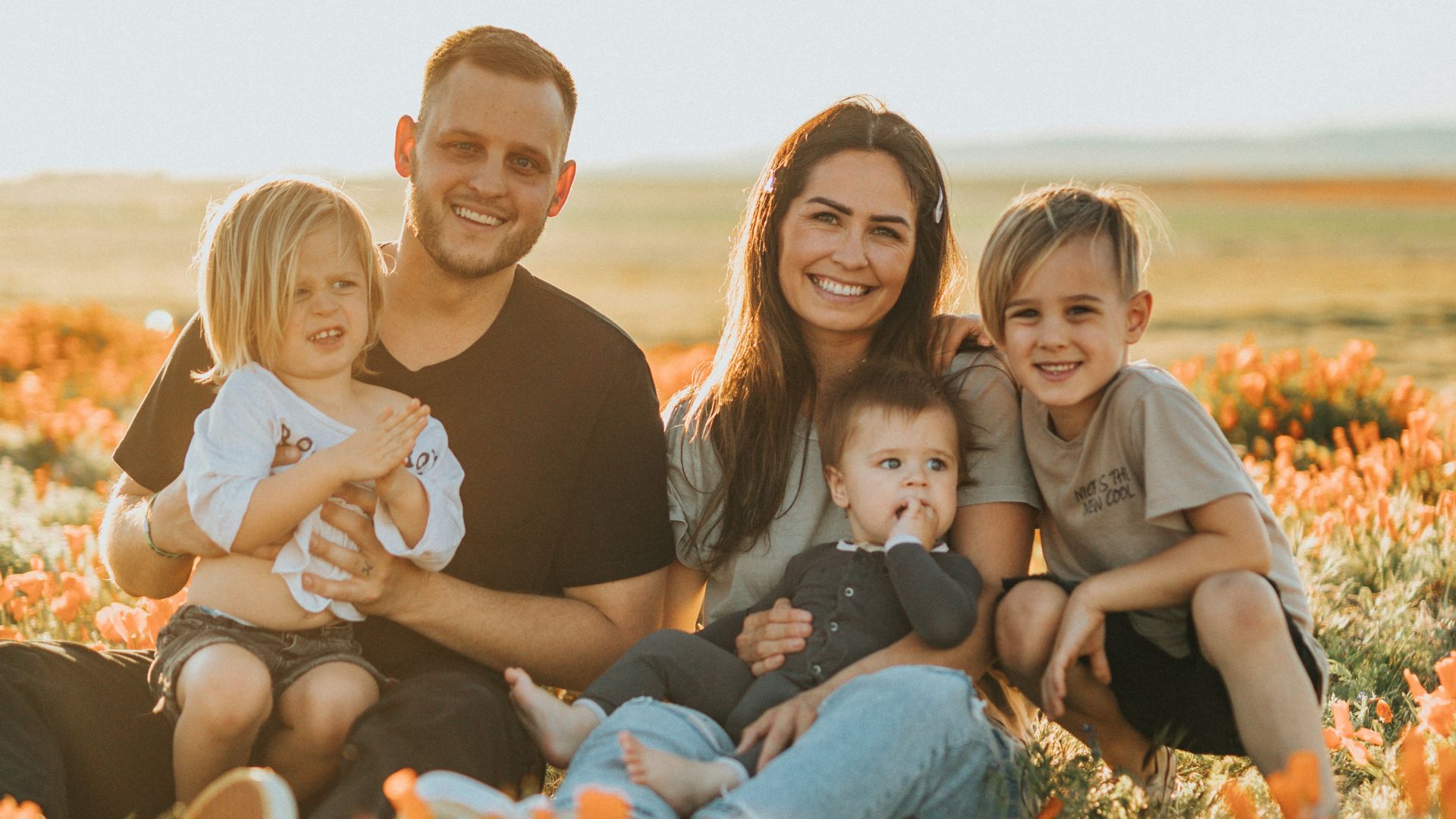 3 women and 2 men sitting on green grass field during daytime