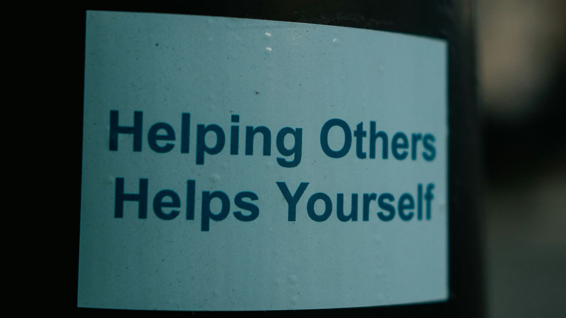 a sticker on a pole that says helping others helps yourself