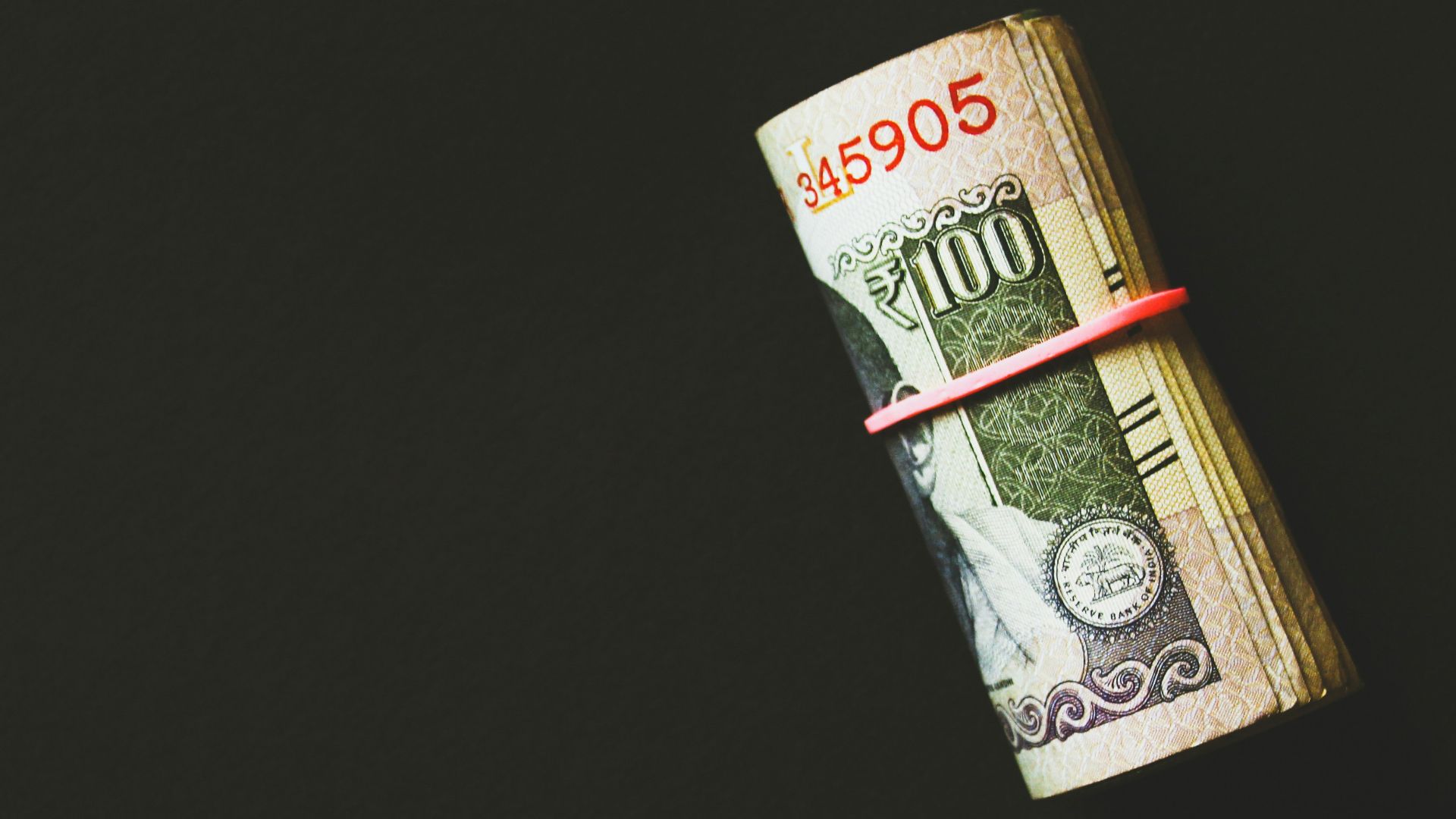 a roll of money wrapped in a red ribbon