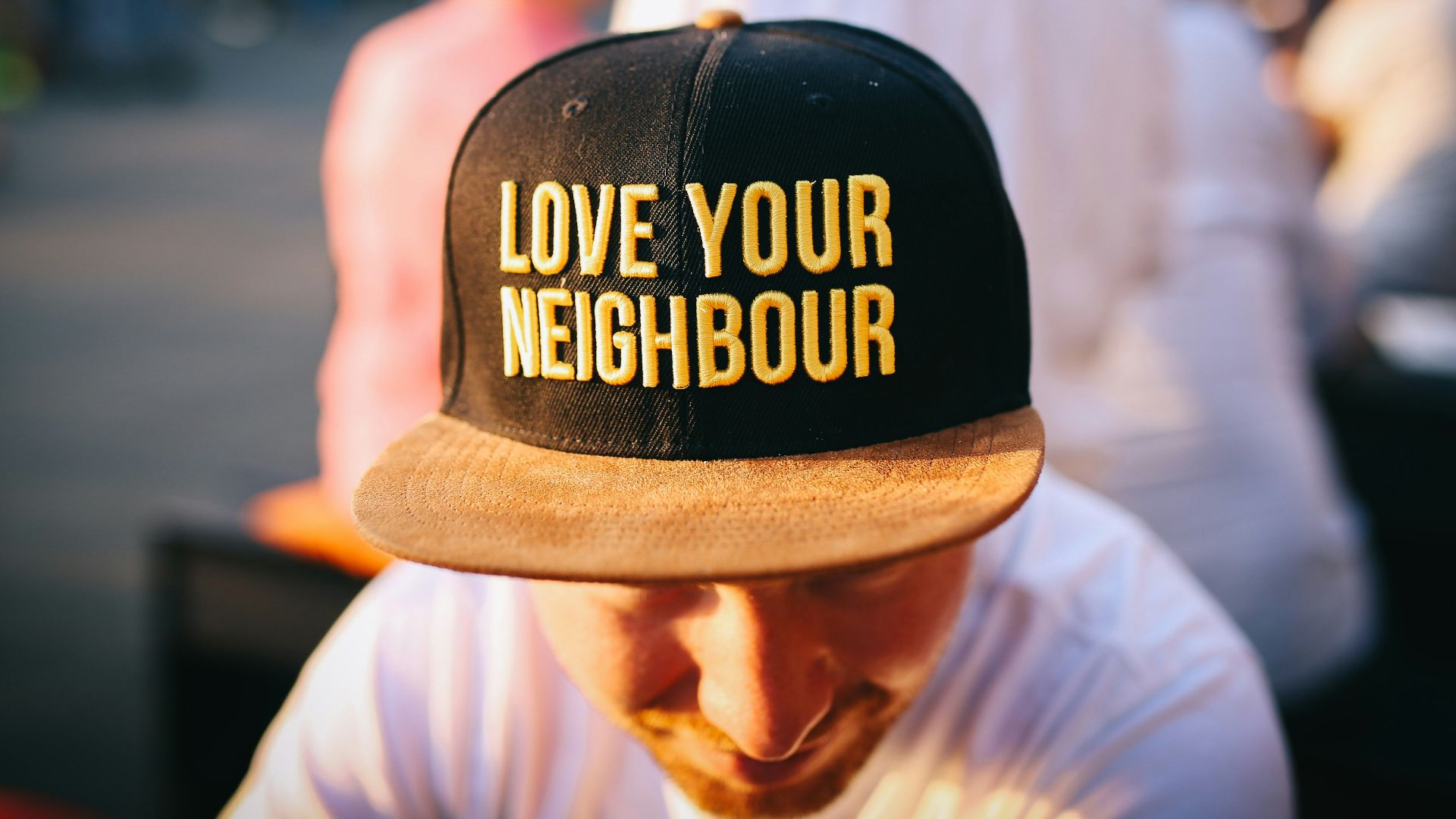 man wearing black cap with love your neighbour print during daytime