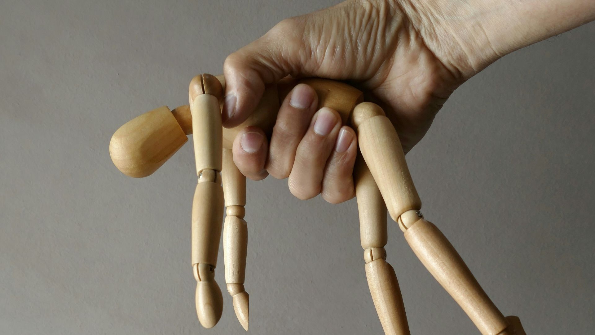 person holding brown wooden mannequin