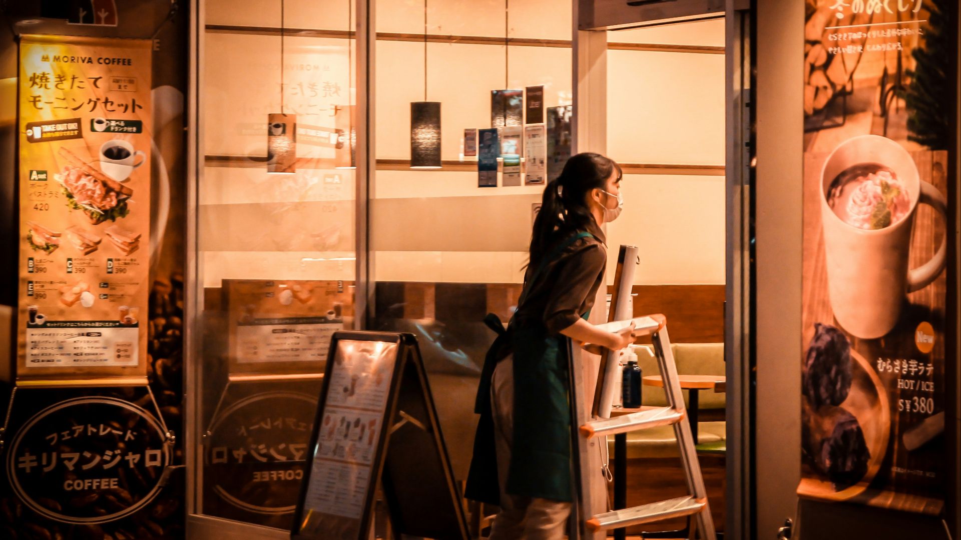 a woman standing outside of a coffee shop at night