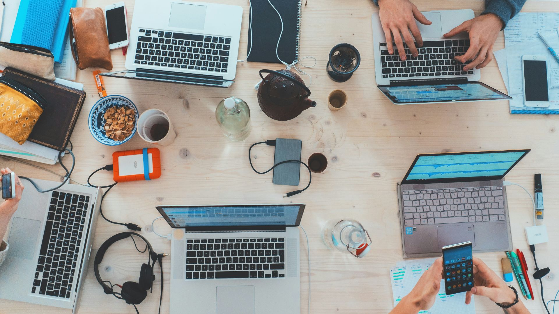 people sitting down near table with assorted laptop computers
