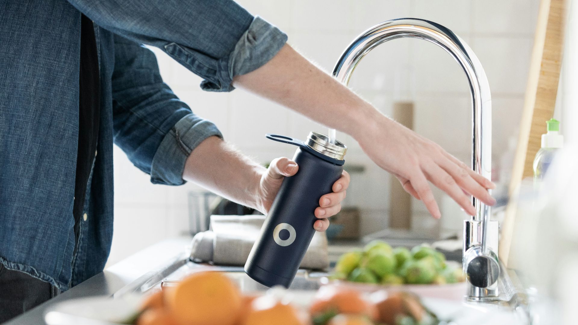 person in blue denim jacket holding stainless steel bottle