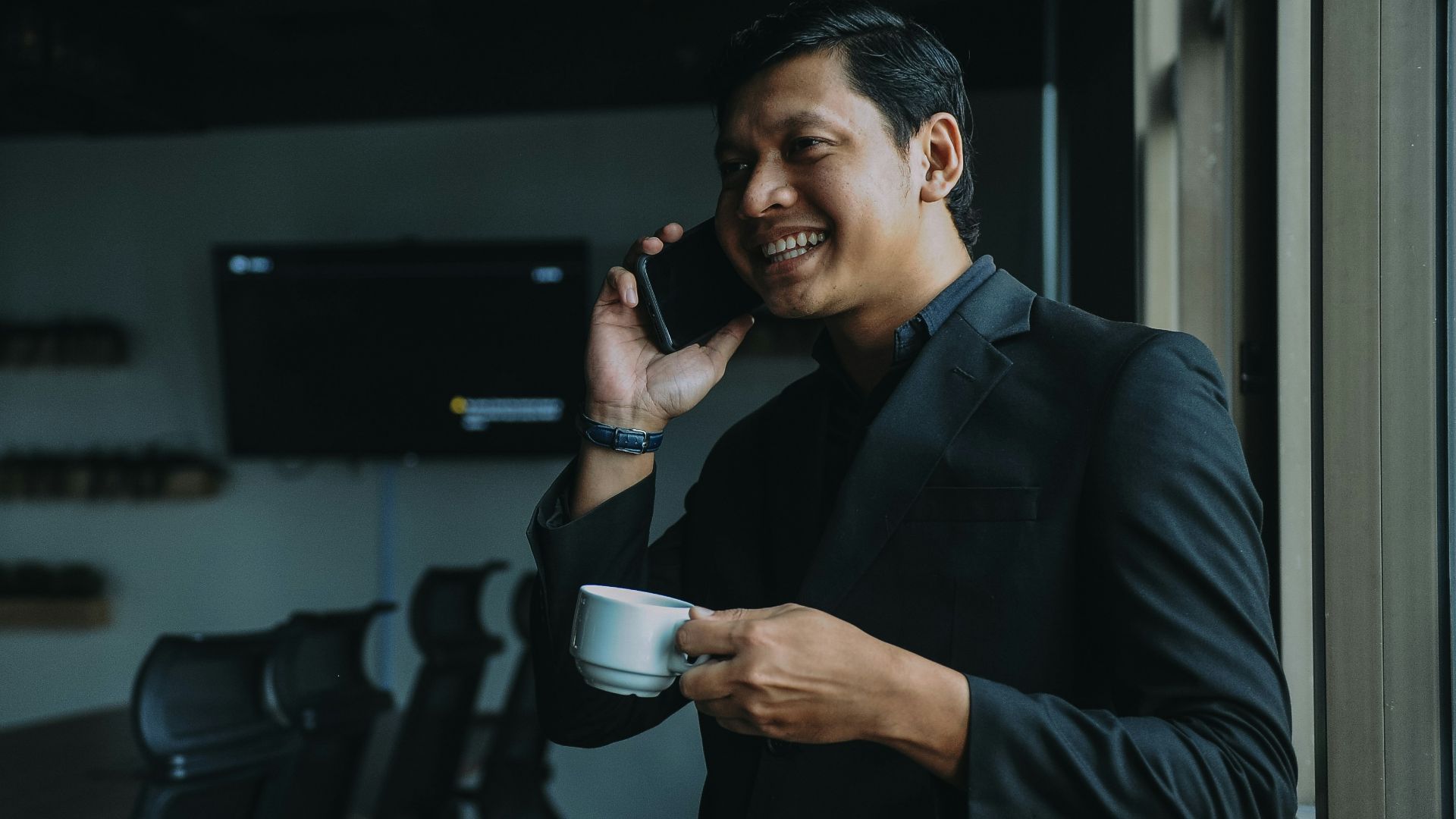 smiling man holding cup and using smartphone