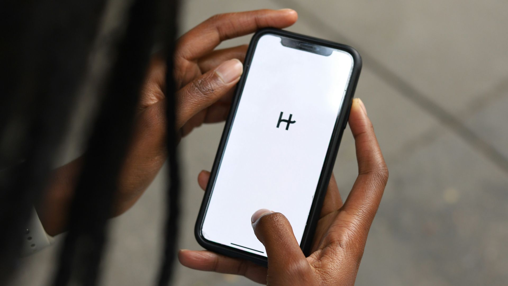 a woman holding a cell phone with a h on the screen