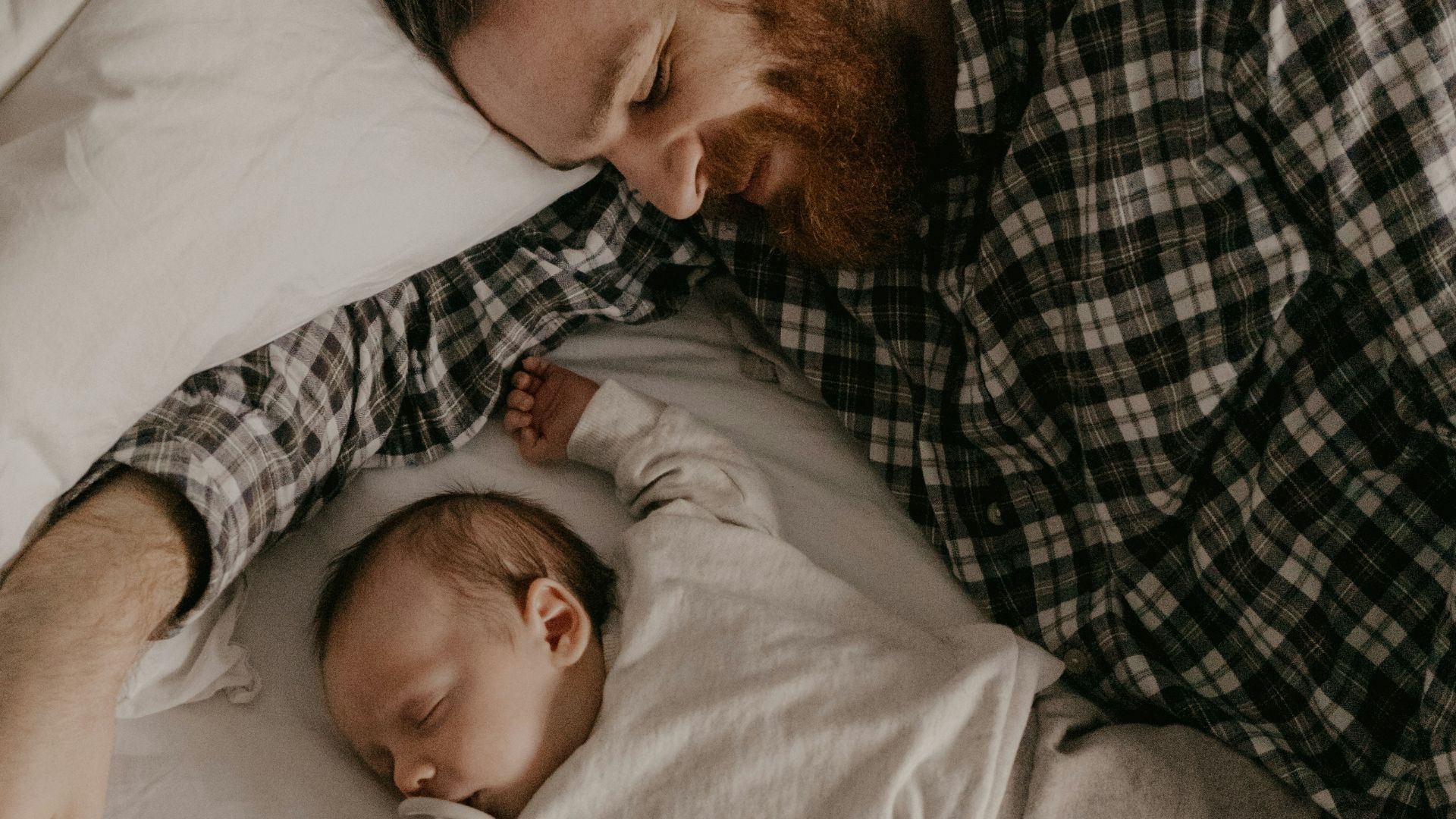 a man laying in bed with a sleeping baby
