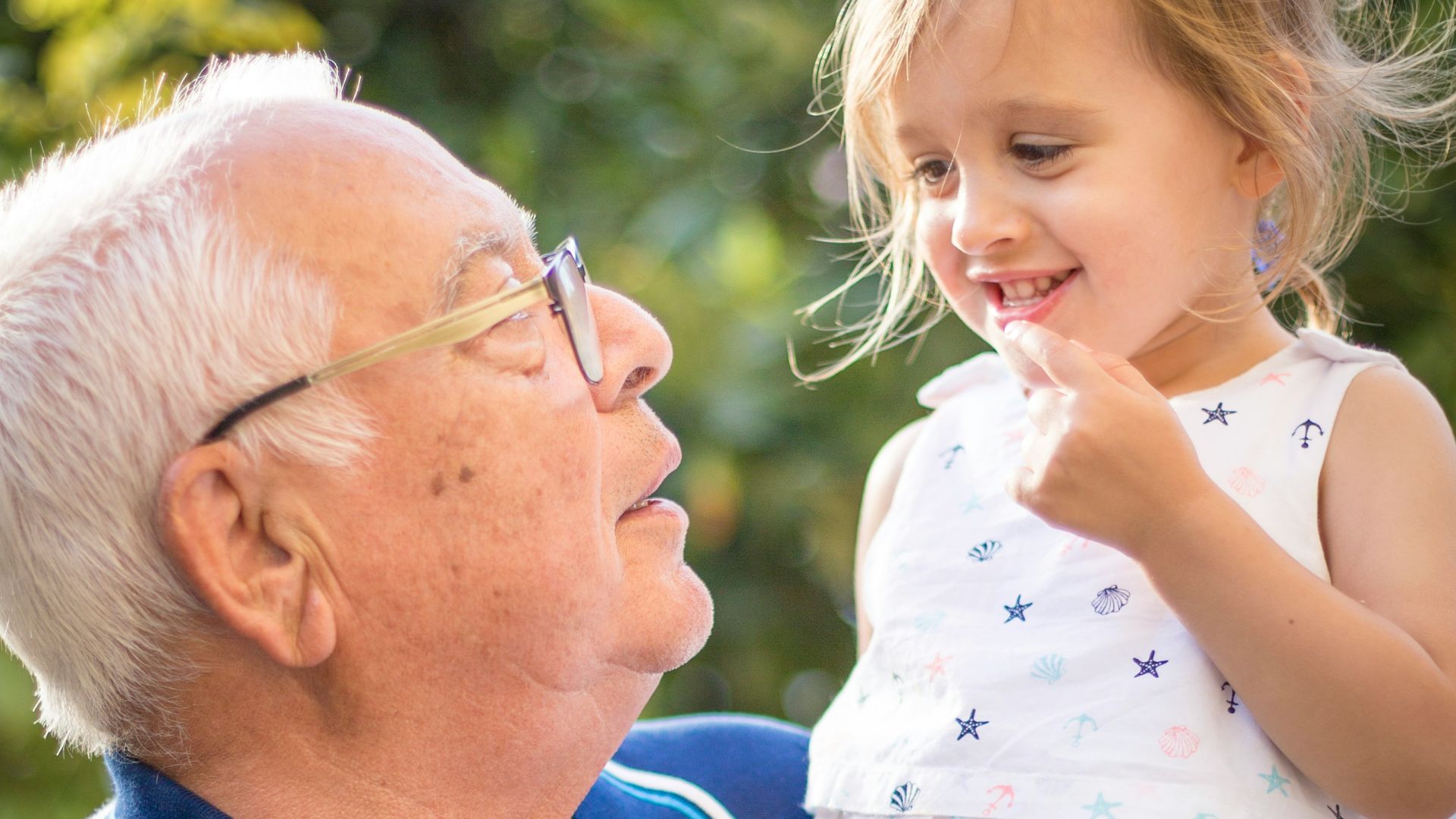 man in blue polo shirt carrying girl in white and pink floral dress