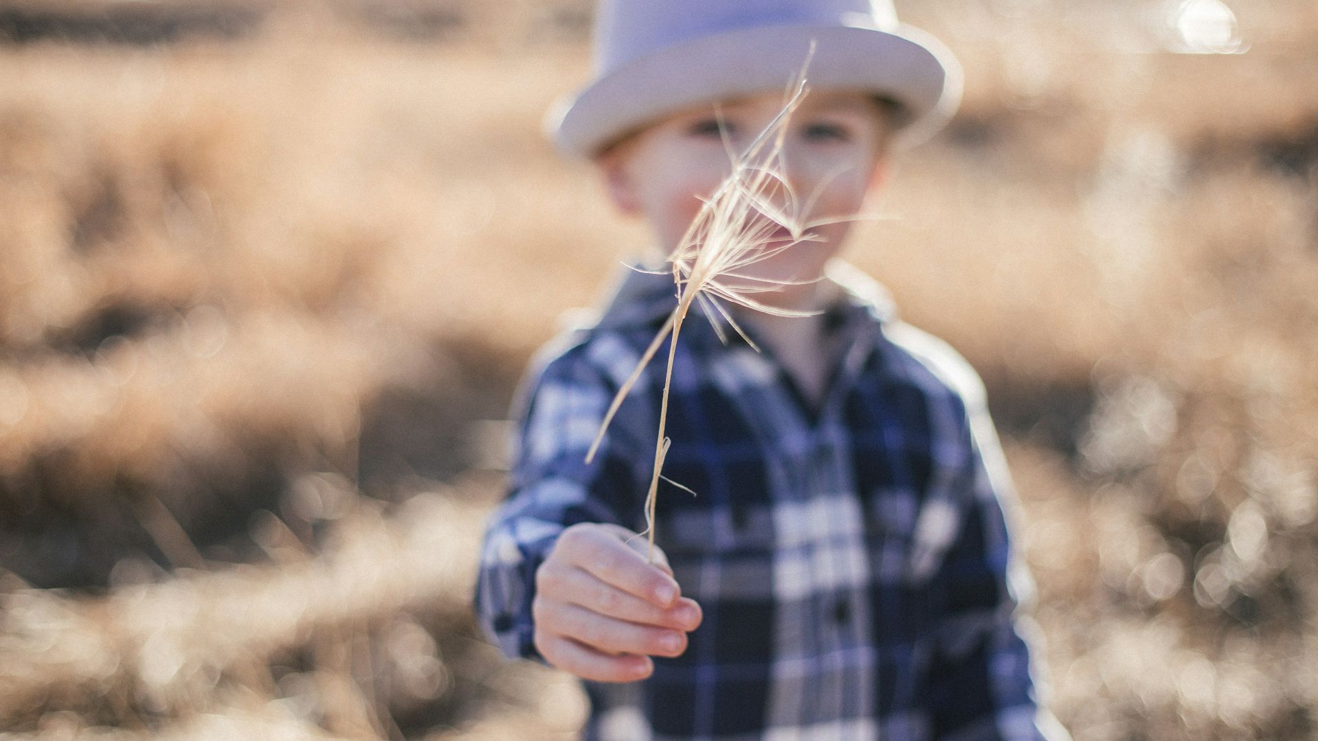 selective focus photography of boy standing near outdoor during daytime