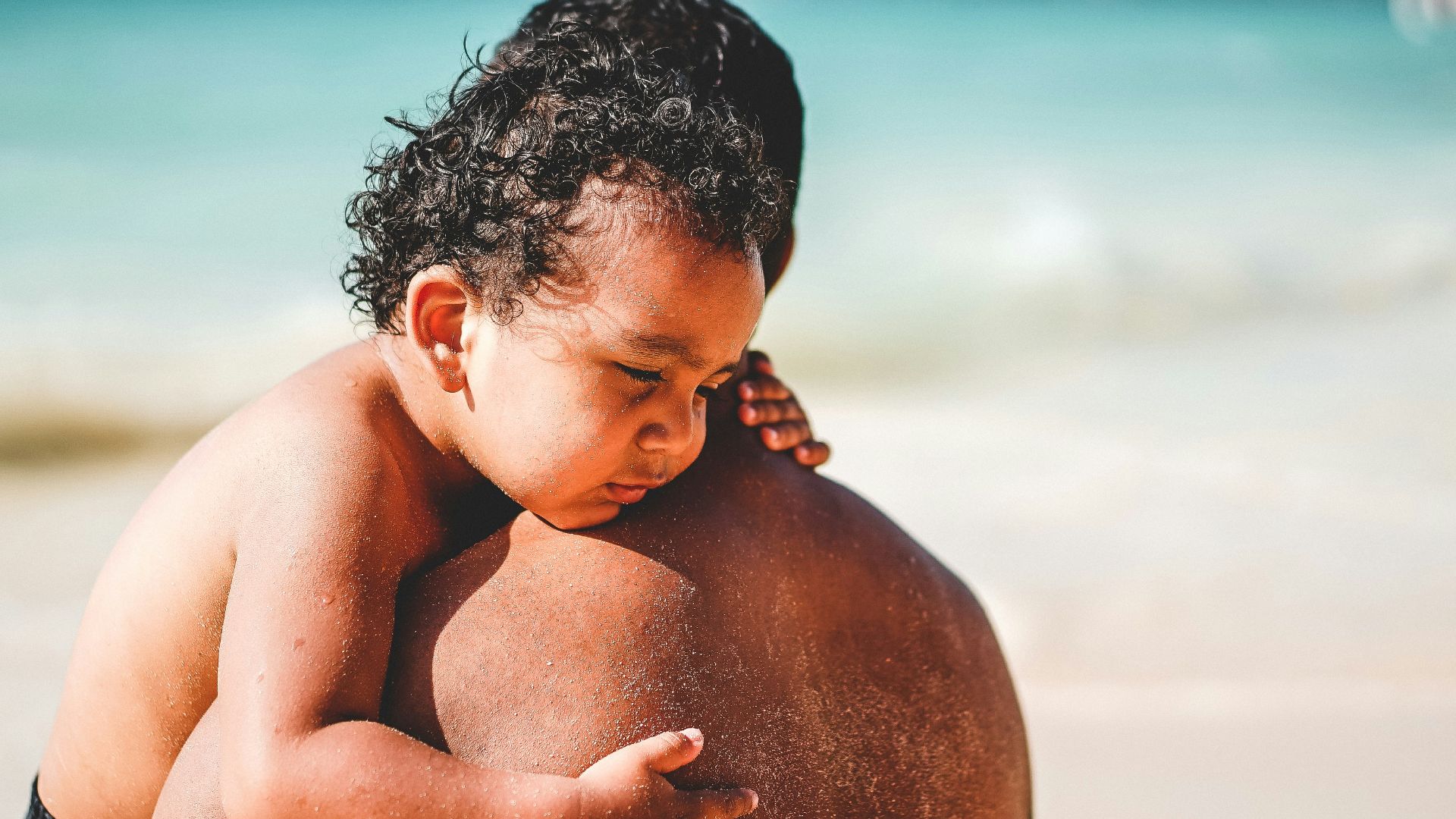 man carrying a boy on seashore