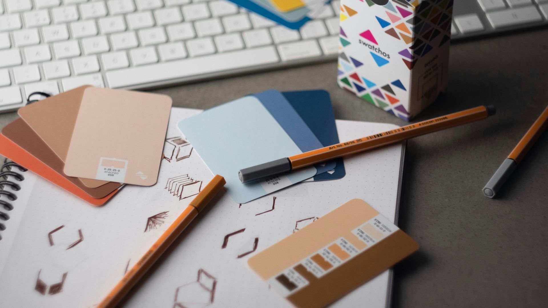 a desk with a keyboard, pencils, and various color samples