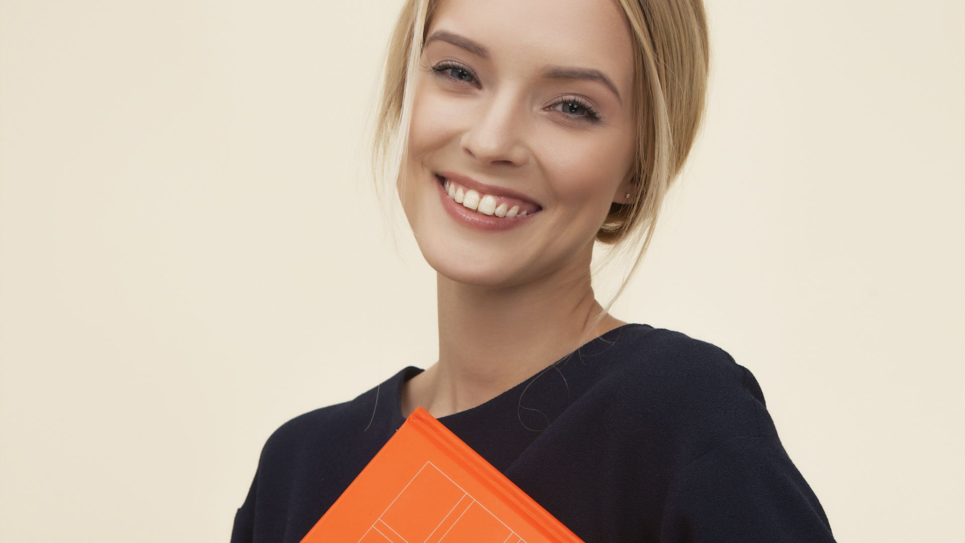 smiling woman standing while holding orange folder