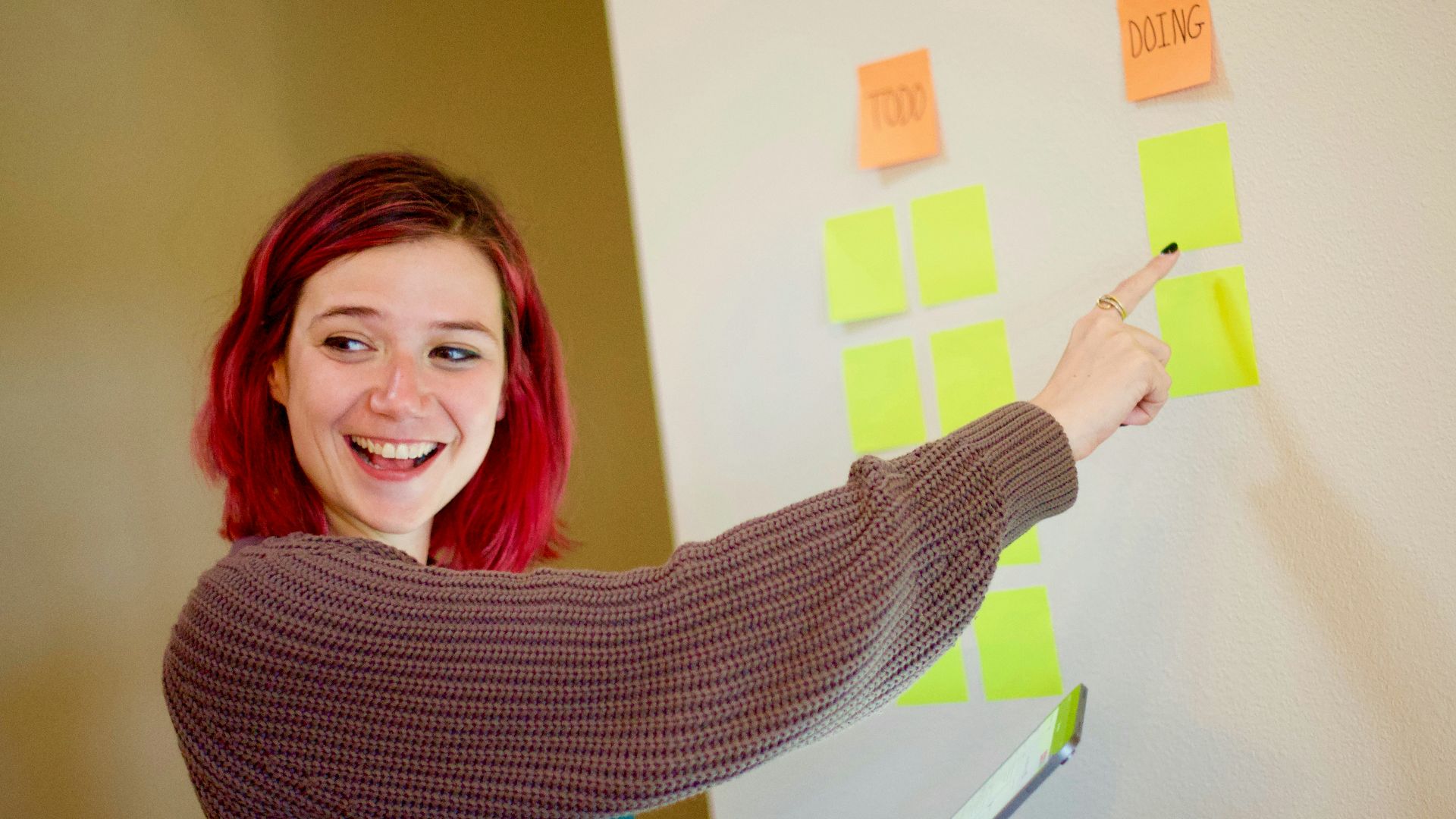 woman in gray sweater holding white and yellow sticky notes