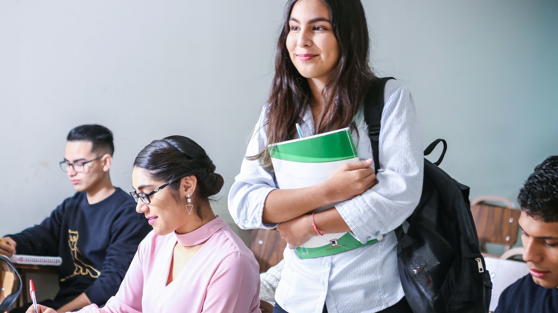 woman carrying white and green textbook