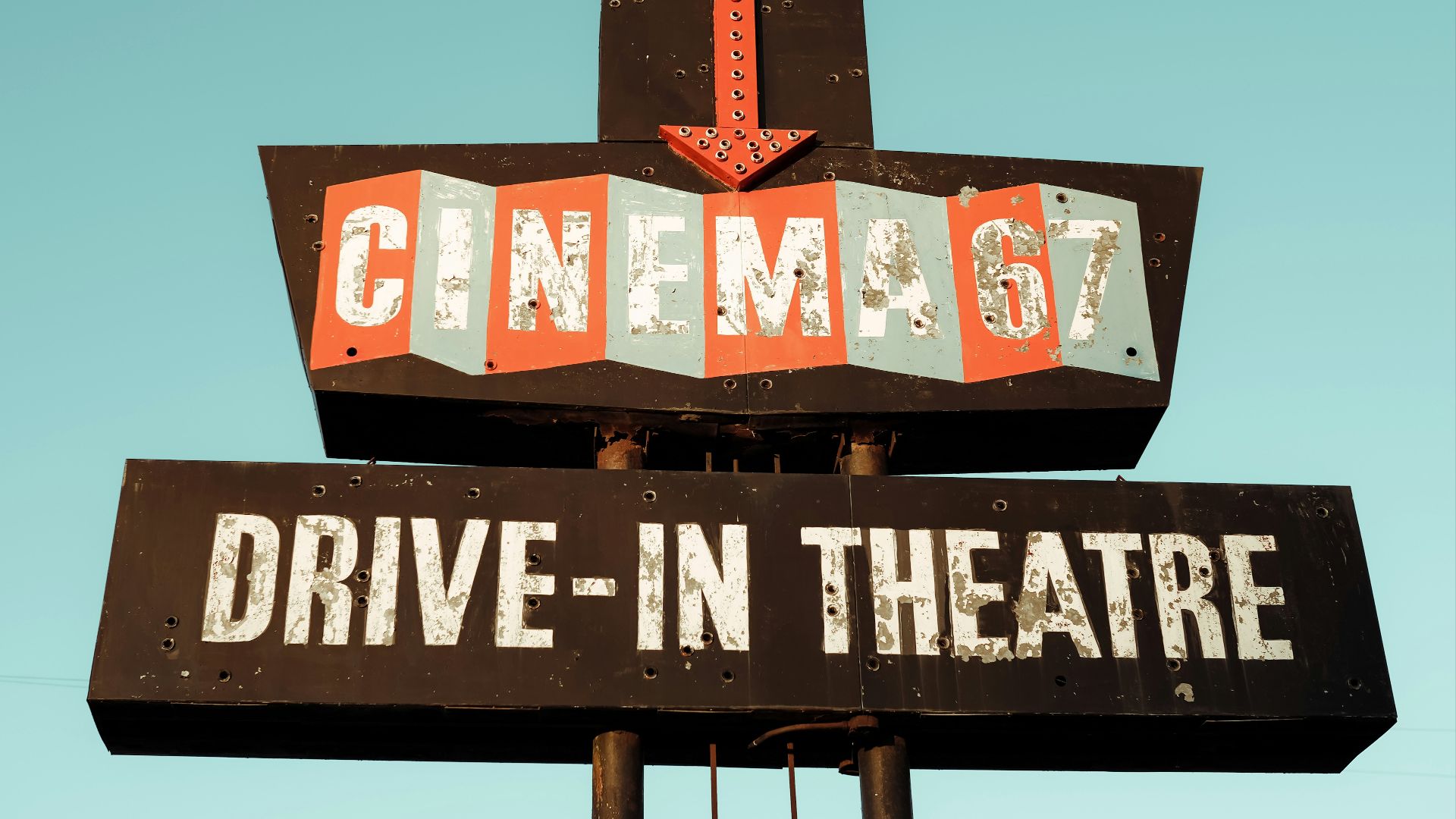 a sign for a drive - in theatre with a sky background