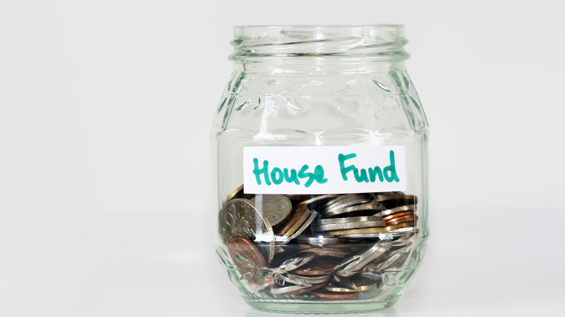 coins in clear glass jar with house fund sign