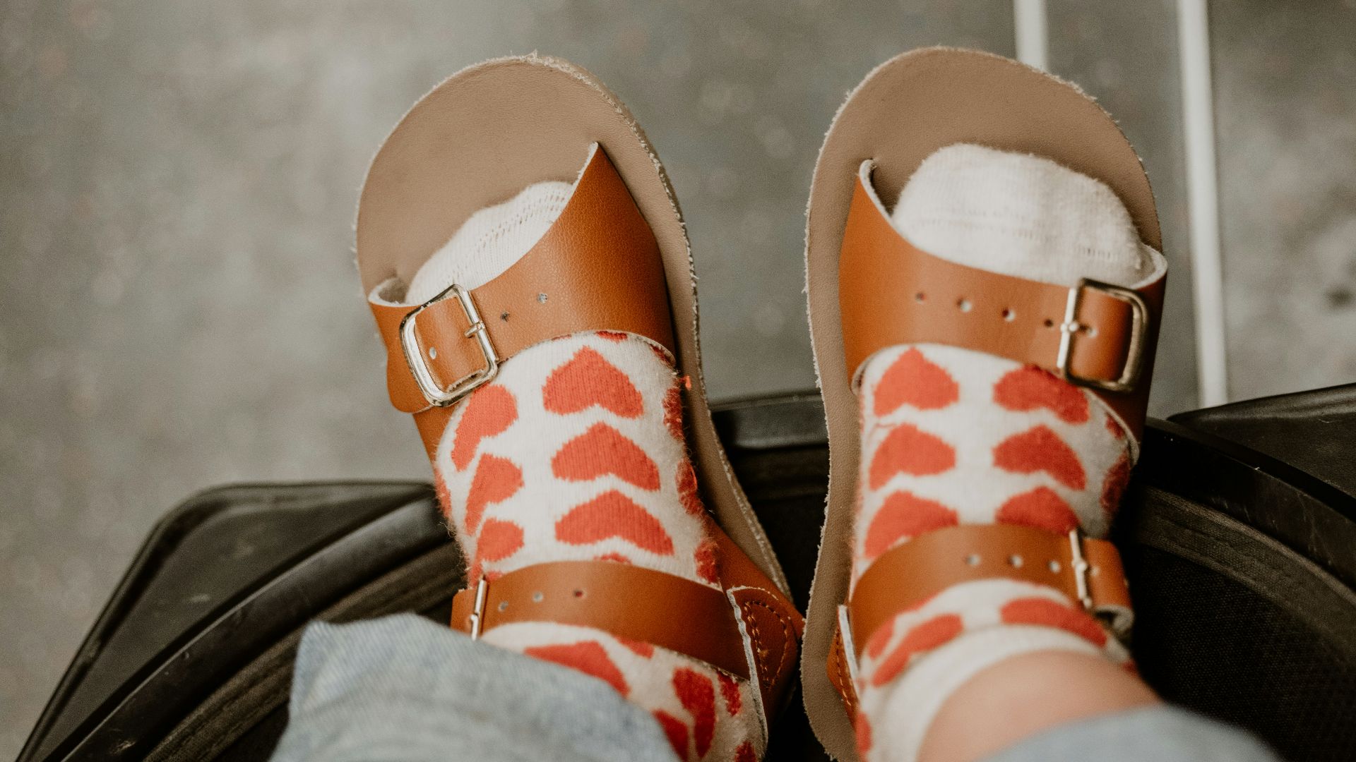 a person's feet in sandals sitting on top of a piece of luggage