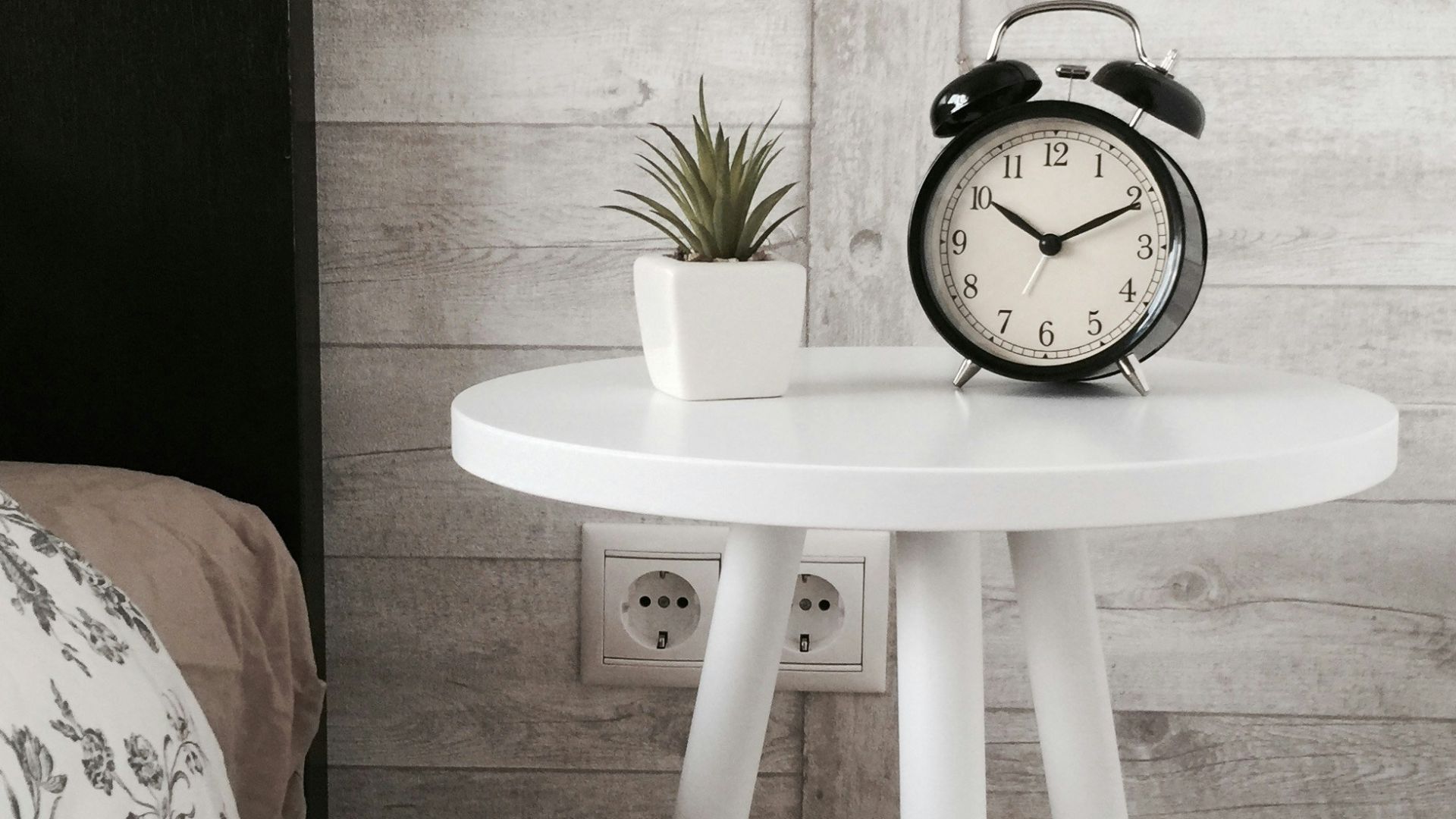 black alarm clock at 10:10 on white wooden table near table