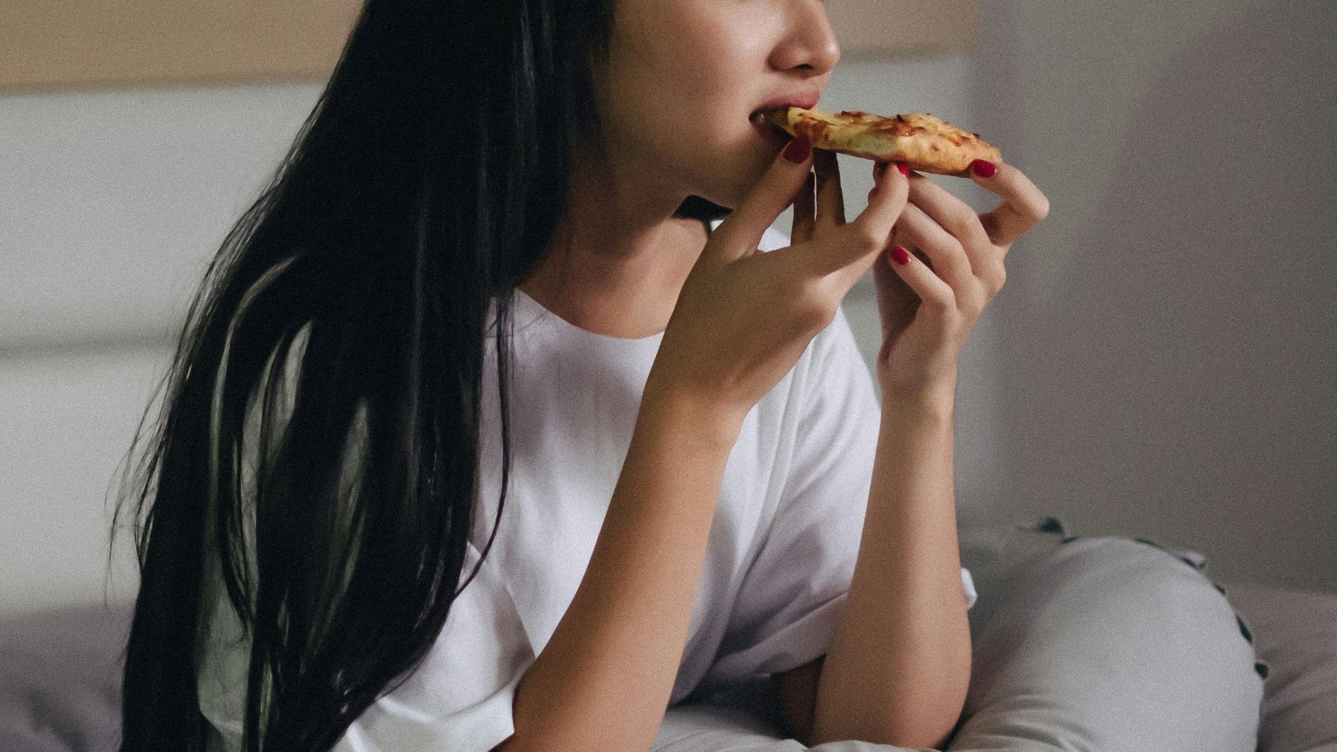 sitting woman in bed eating pastry