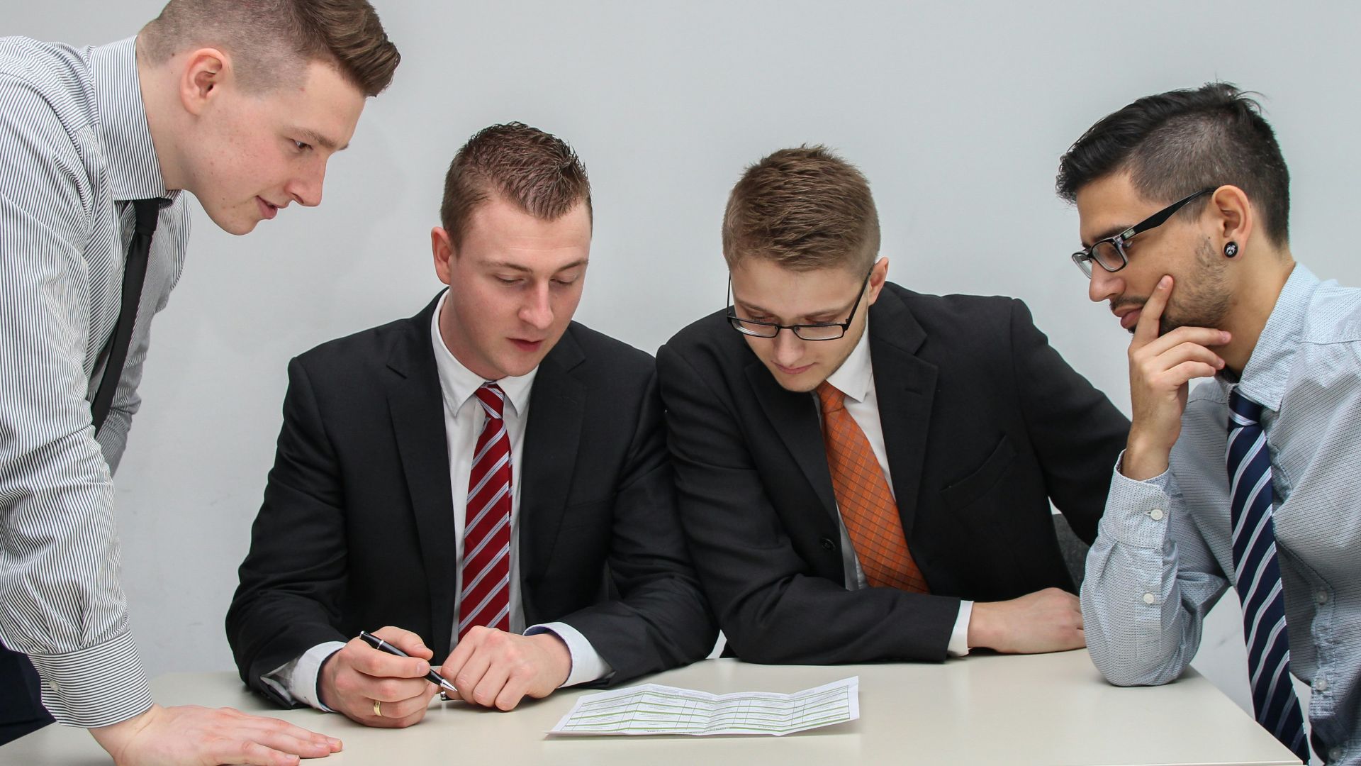 four men looking to the paper on table