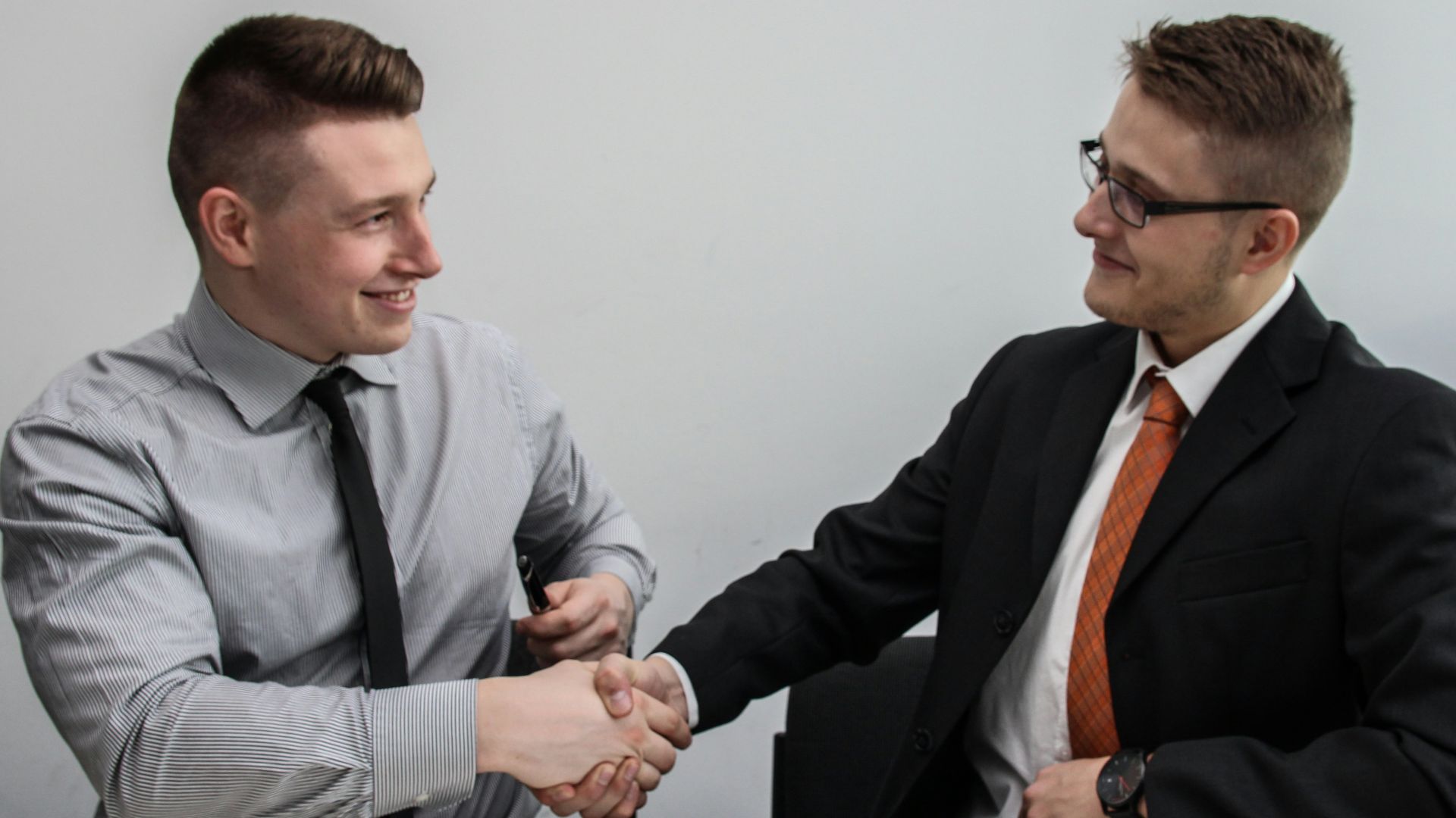 two men facing each other while shake hands and smiling
