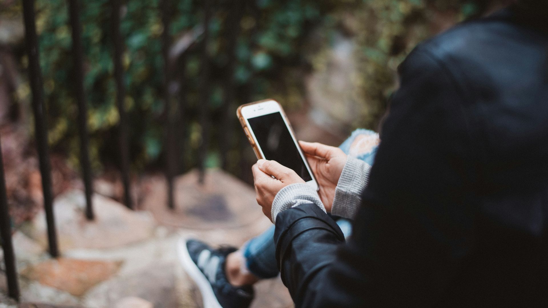 person holding white smartphone sitting on stair