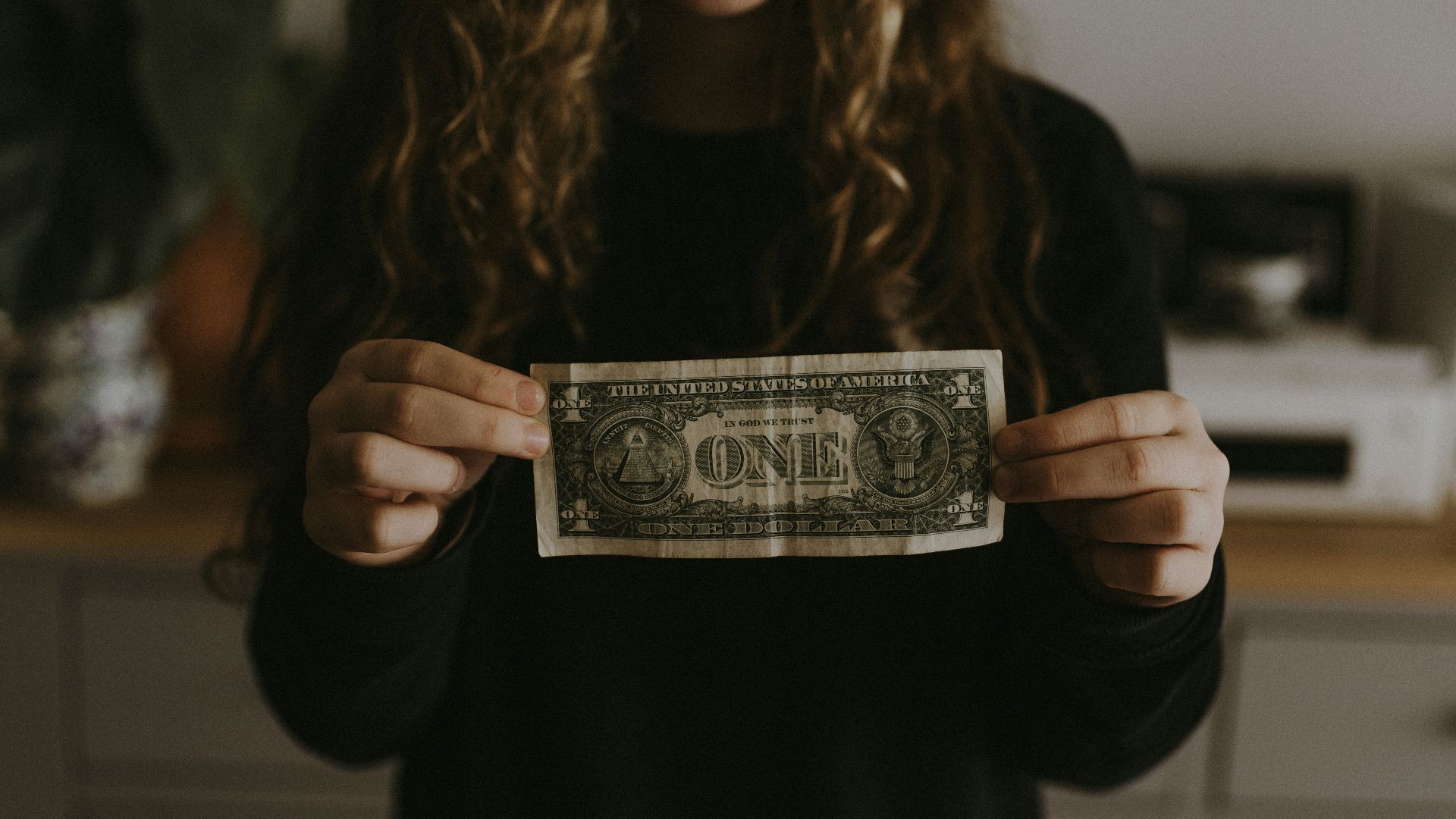 girl holding 1 U.S. dollar banknote