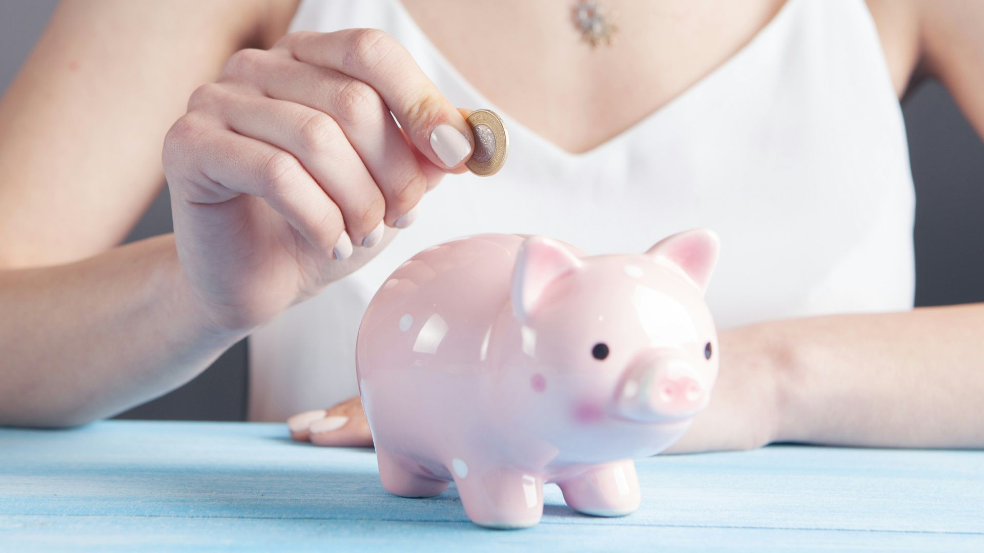 woman in white tank top holding pink pig figurine