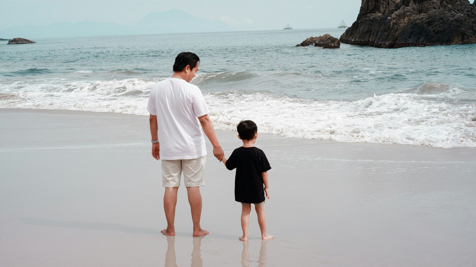 a man and a child walking on a beach