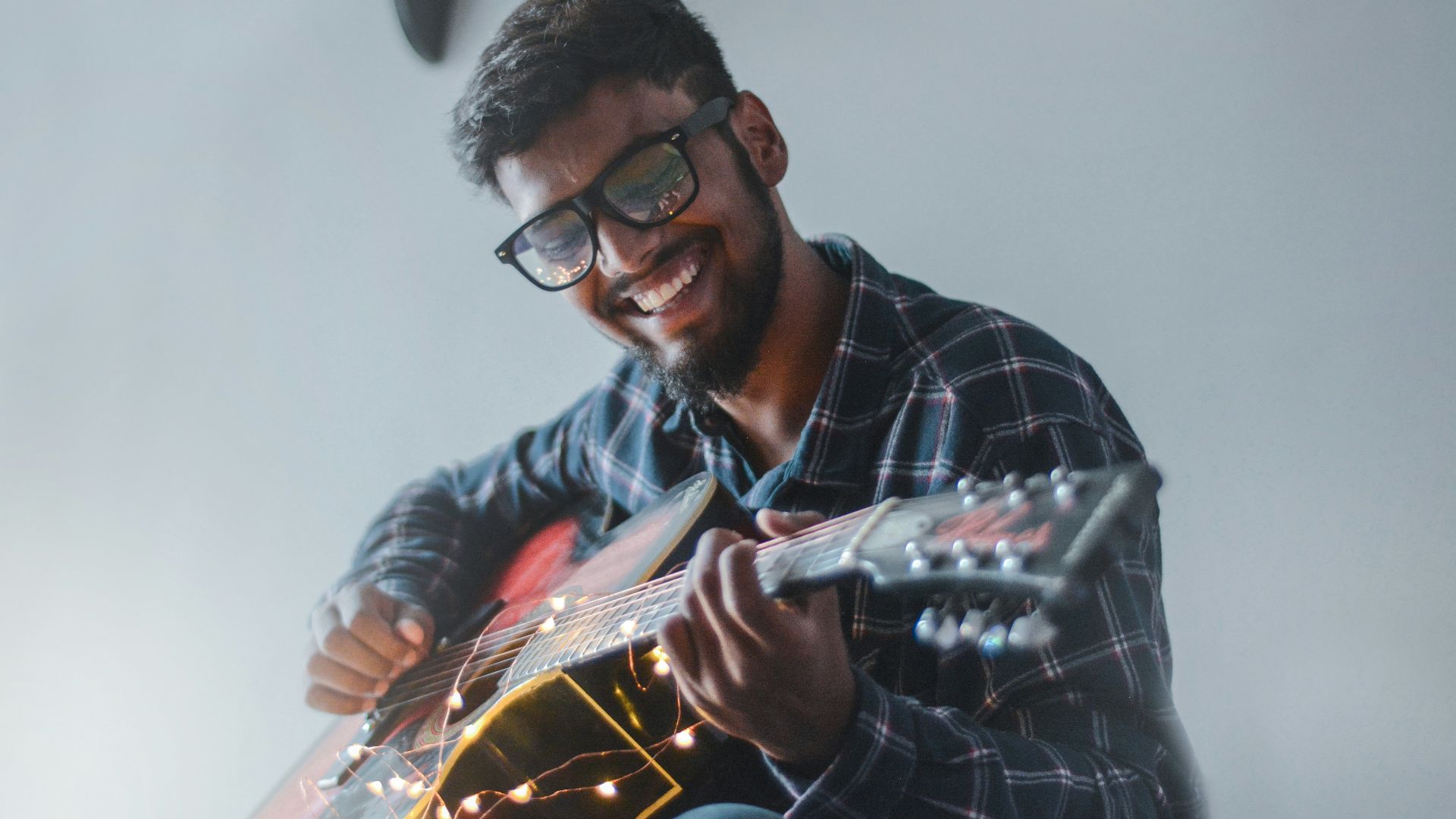 smiling man sitting while playing guitar