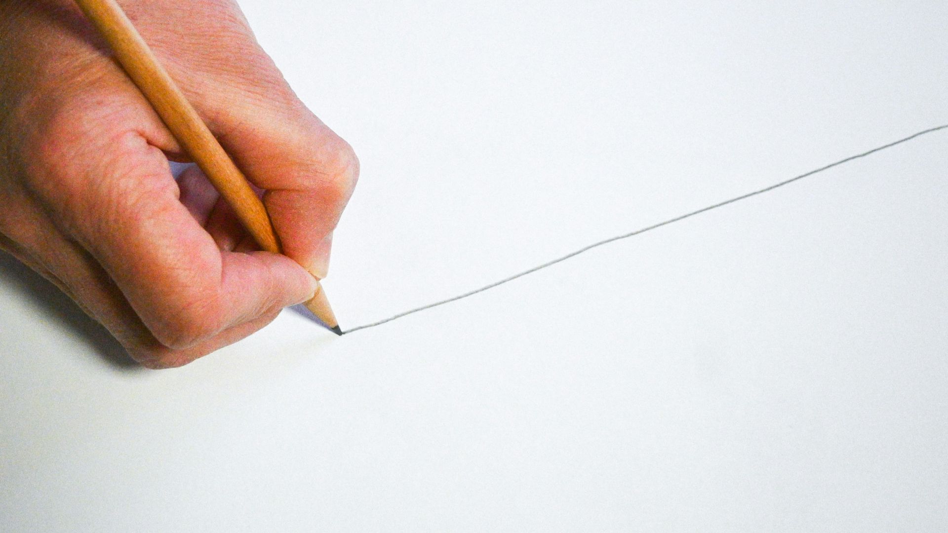 A person holding a pencil and writing on a piece of paper
