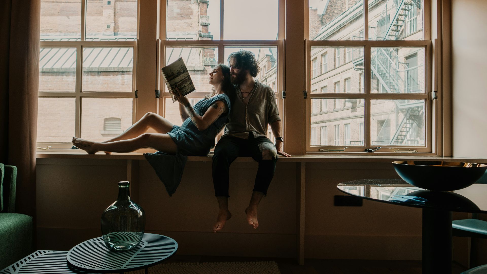 woman in white long sleeve shirt sitting on brown wooden table reading book