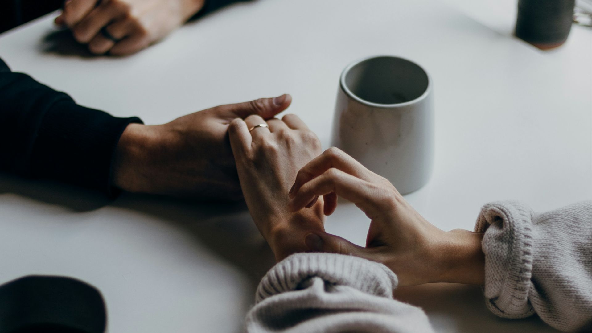 person in black long sleeve shirt holding white ceramic mug