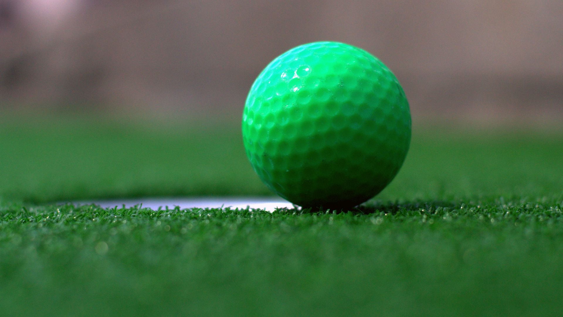 a green golf ball sitting on top of a green field