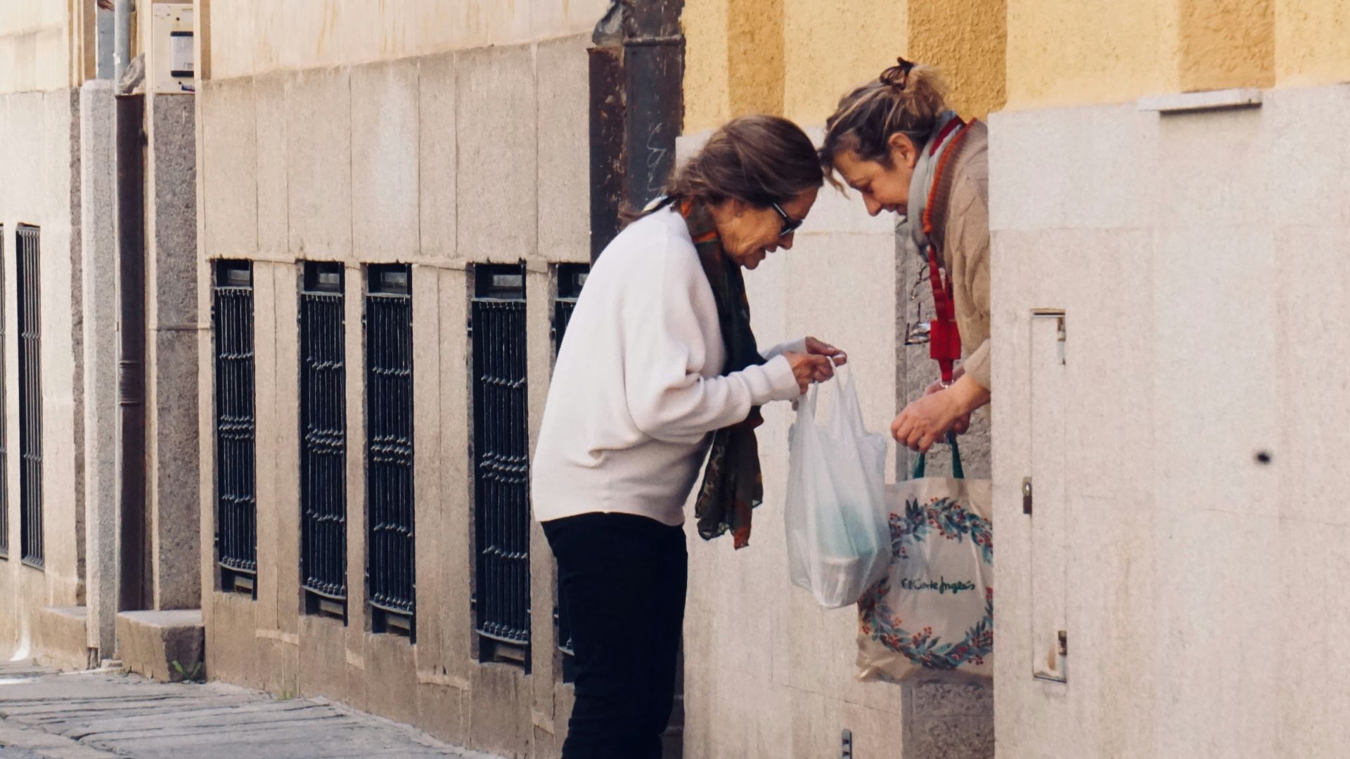 woman in white long sleeve shirt and black pants standing on sidewalk during daytime