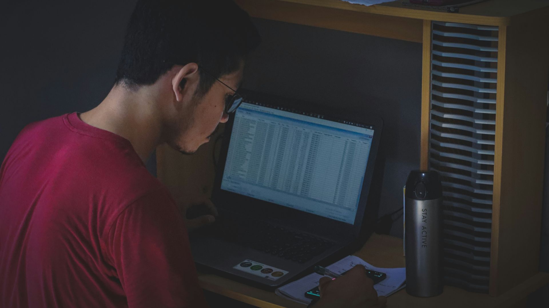 man in red shirt using black laptop computer