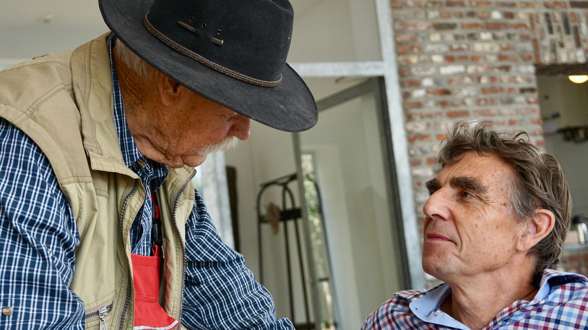 man in blue and white plaid button up shirt wearing black fedora hat