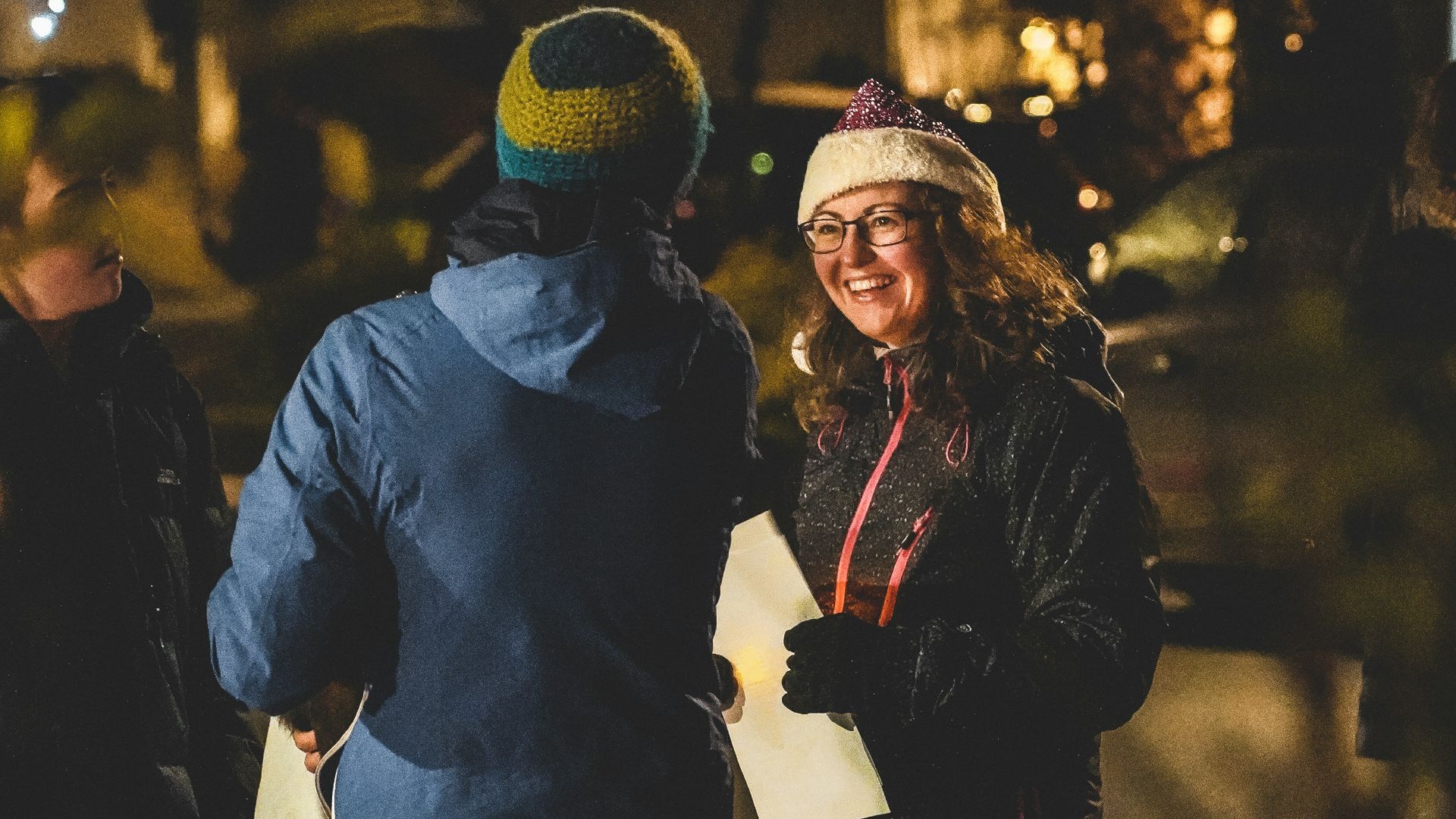 man and woman wearing black jacket and blue denim jeans walking on street during night time