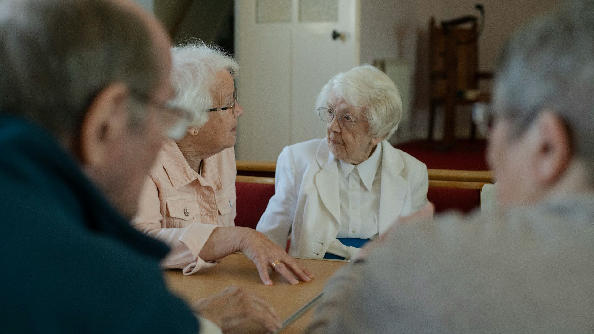 Seniors are sitting around a table, talking.