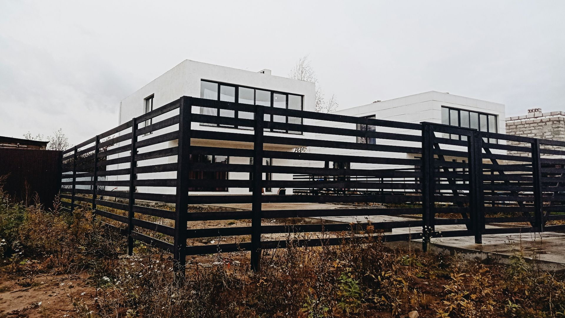 a black and white building sitting on top of a dry grass field
