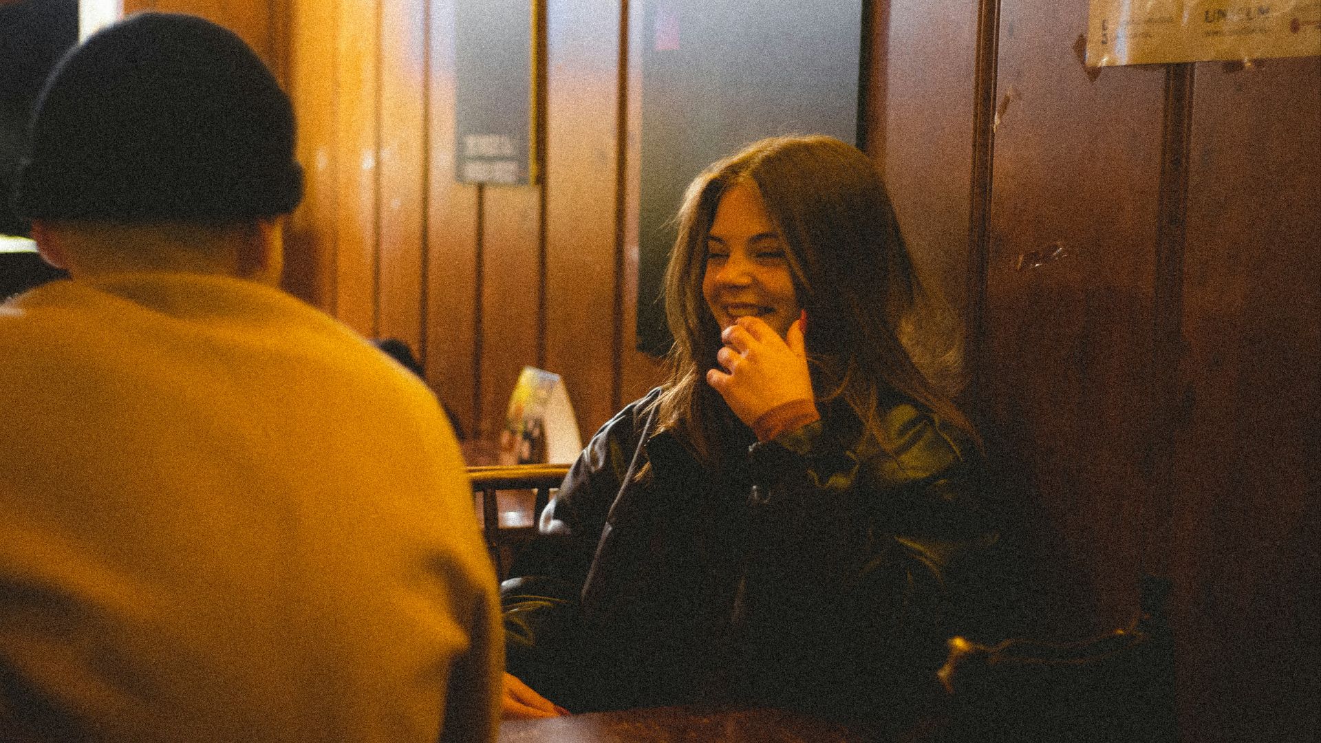a woman sitting at a table talking on a cell phone