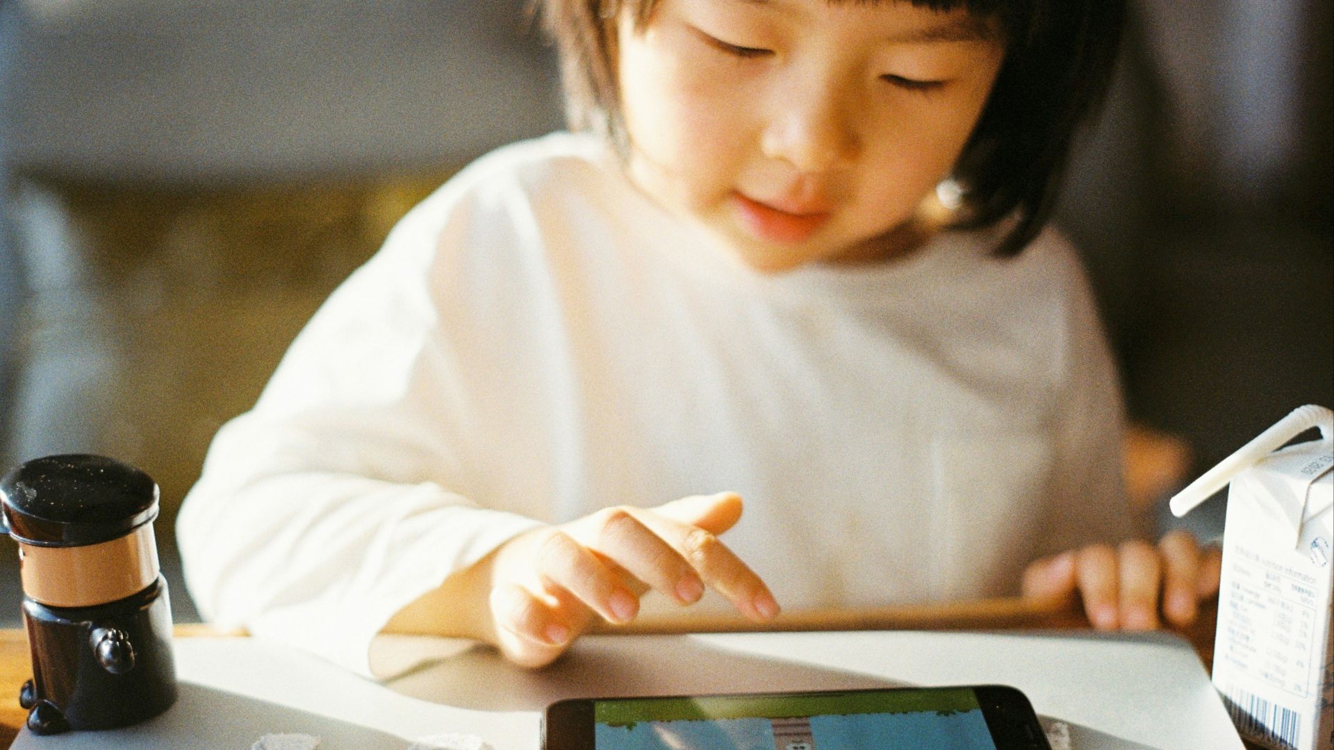 woman in white long sleeve shirt holding black smartphone
