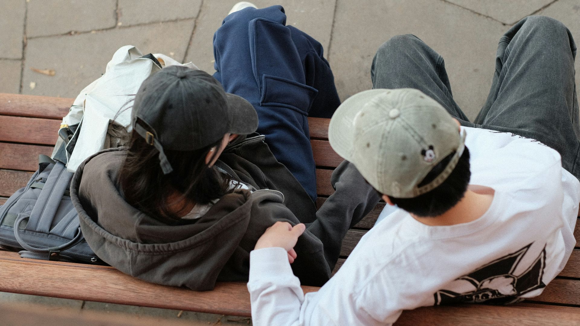 A group of people sitting on top of a wooden bench