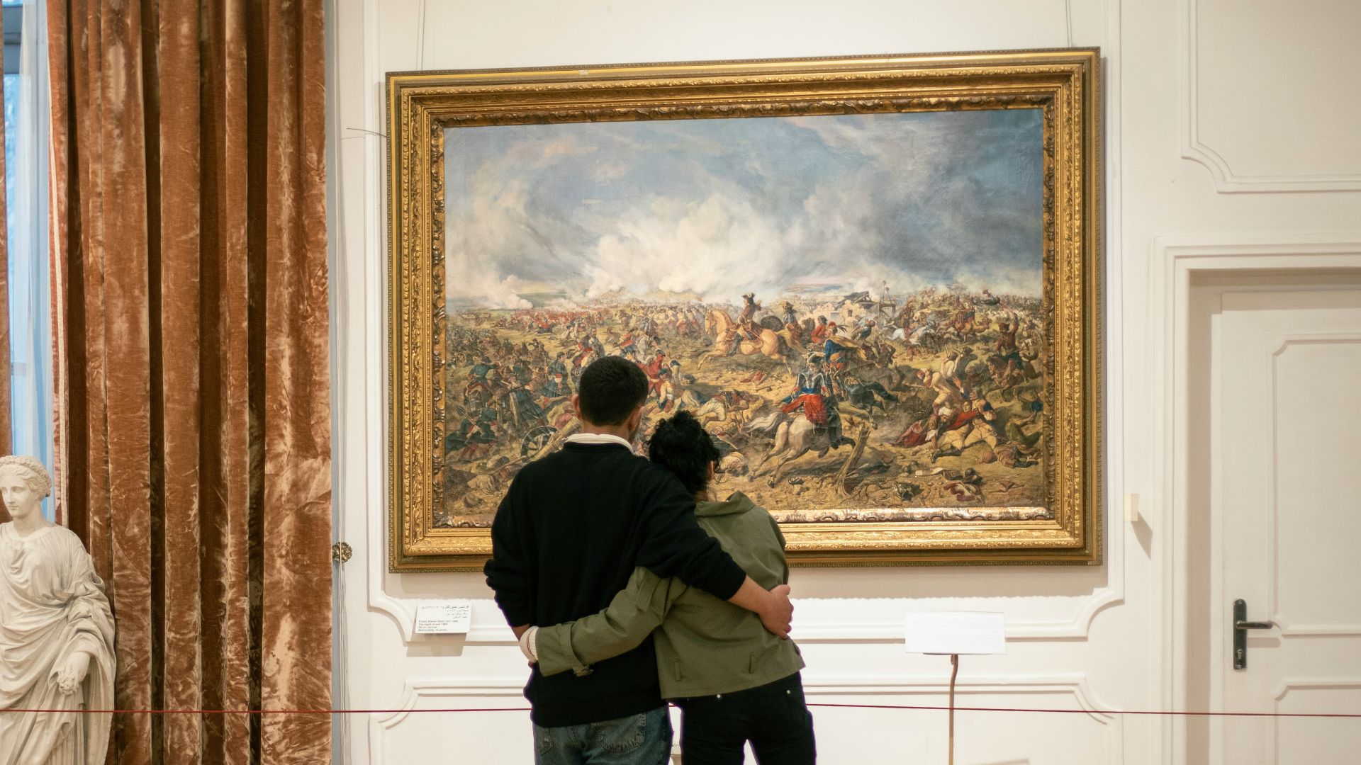 a man and a woman standing in front of a painting