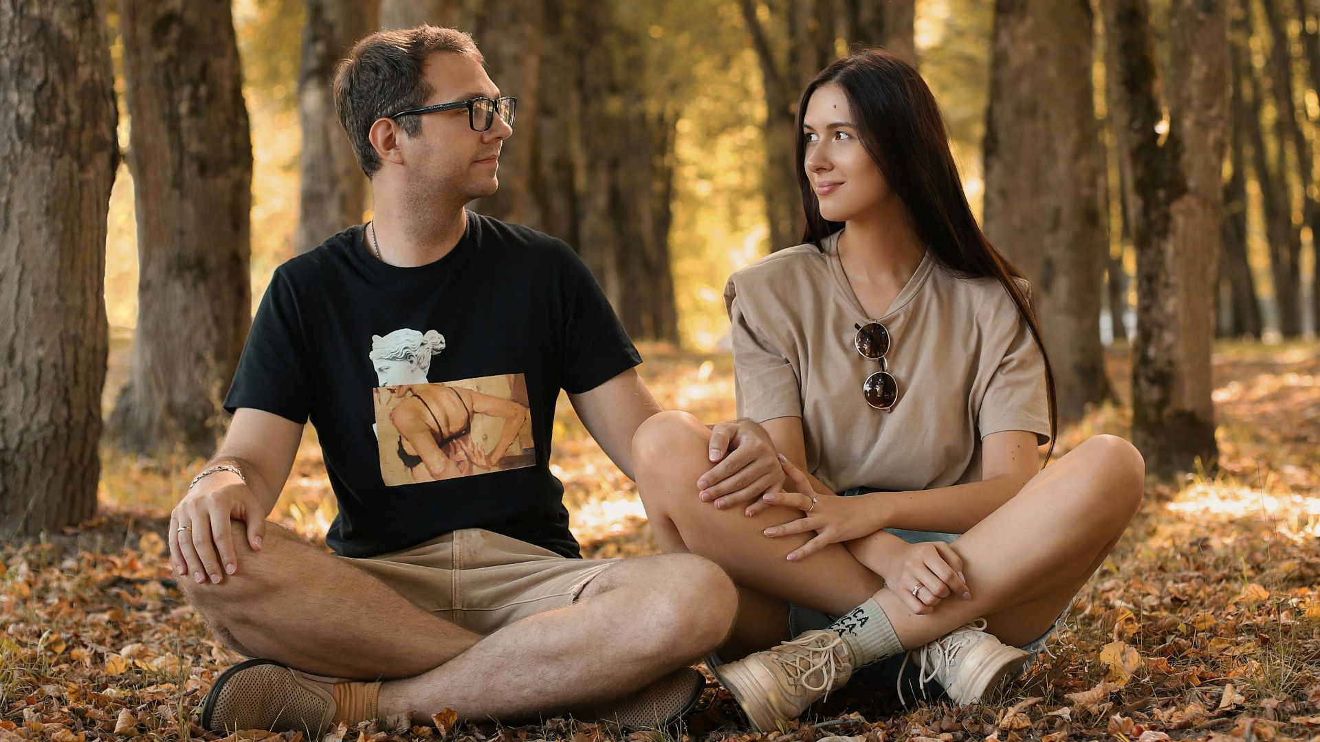 a man and a woman sitting on the ground in a forest