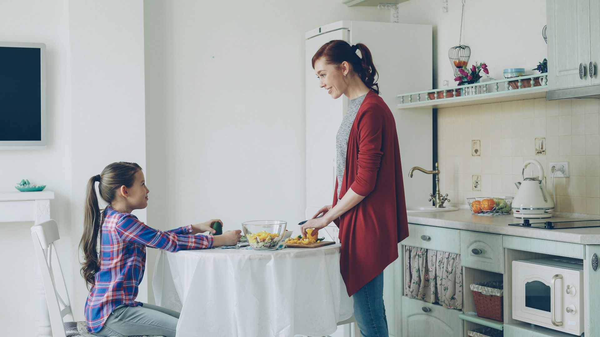 Mother serves her daughter breakfast at a table.