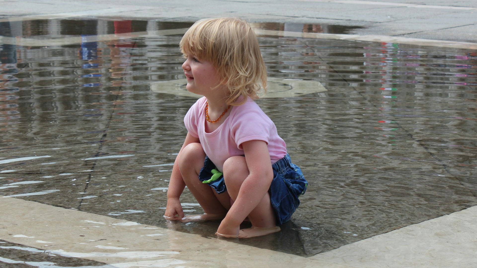 a little girl playing in a puddle of water