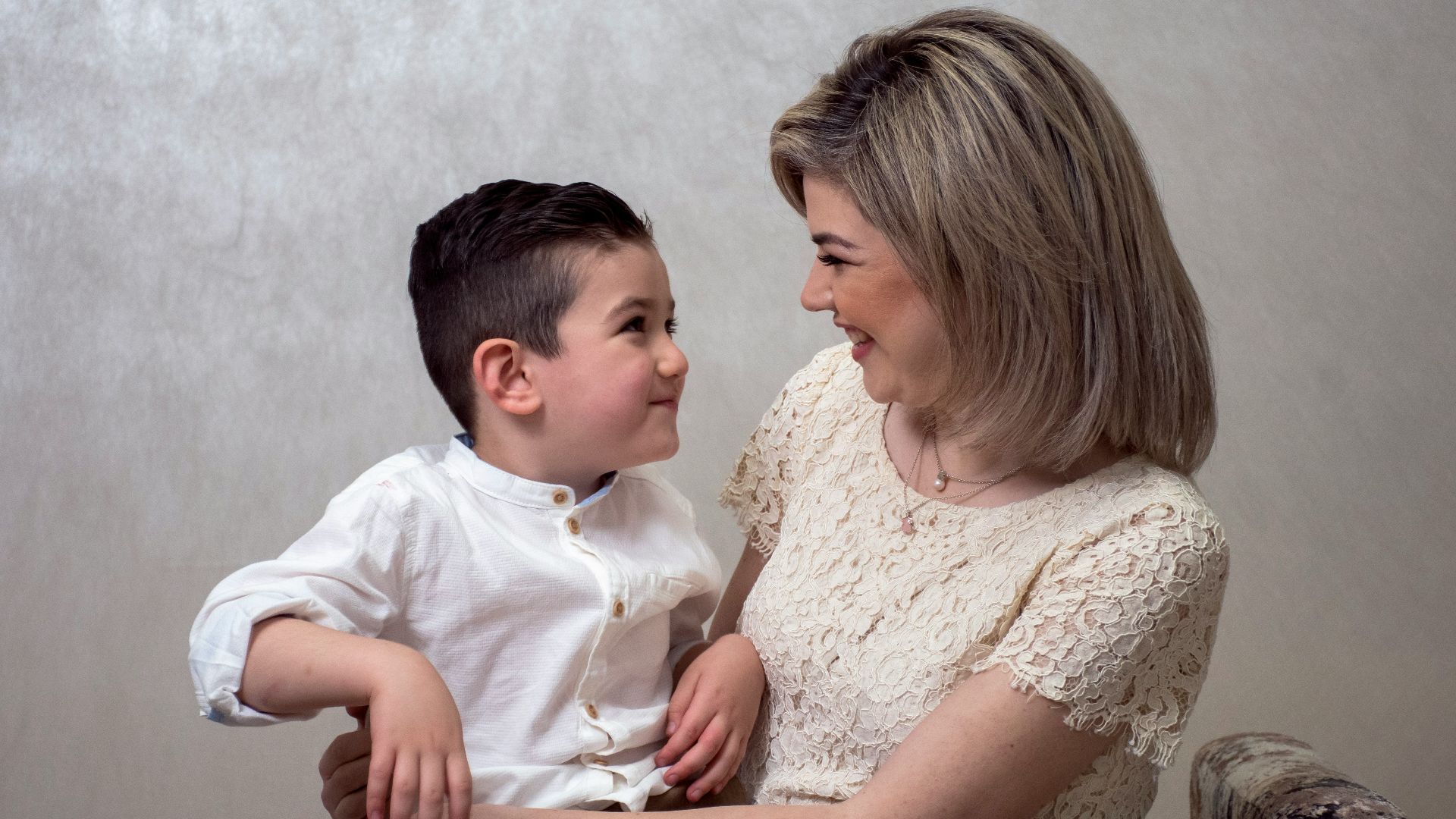 a woman sitting next to a little boy